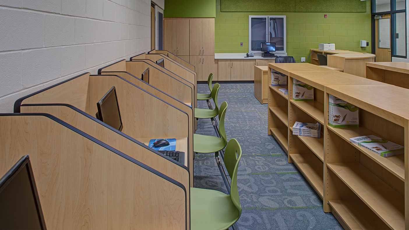 The new library in the center includes individual work stations, each equipped with a computer and multiple bookcases. 